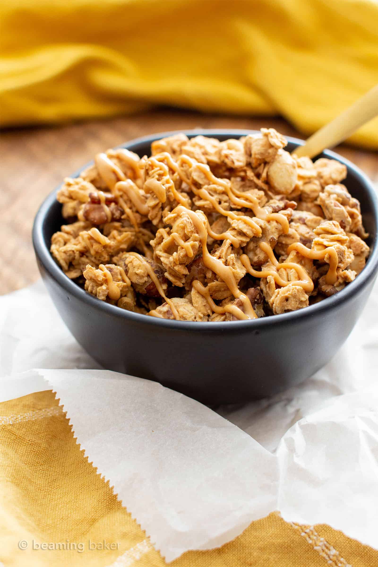 this peanut butter granola recipe in a black bowl with peanut butter drizzled on top