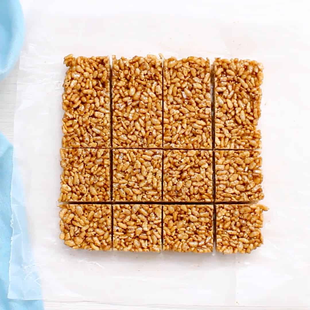 healthy rice krispie treats sliced almost all the way to create 16 bars laying on wax paper