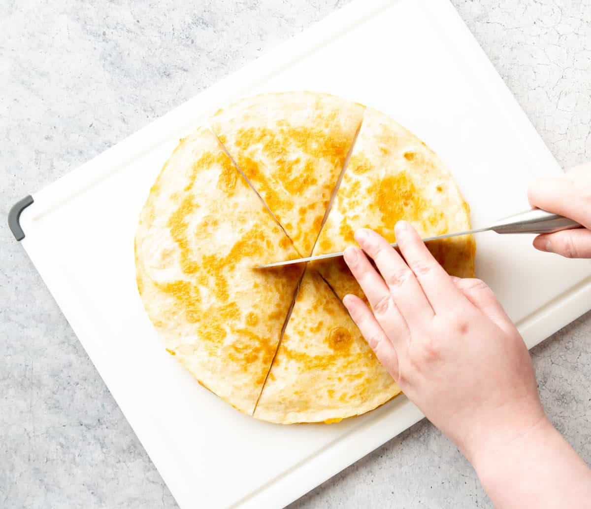 slicing the crisped tortilla into sixths on a cutting board