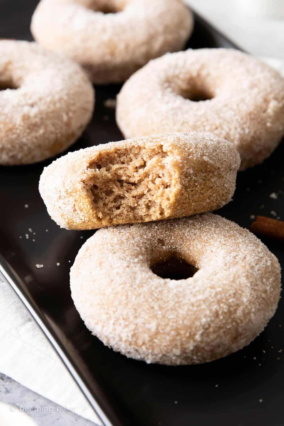 One bitten cinnamon sugar donut perched on top of another