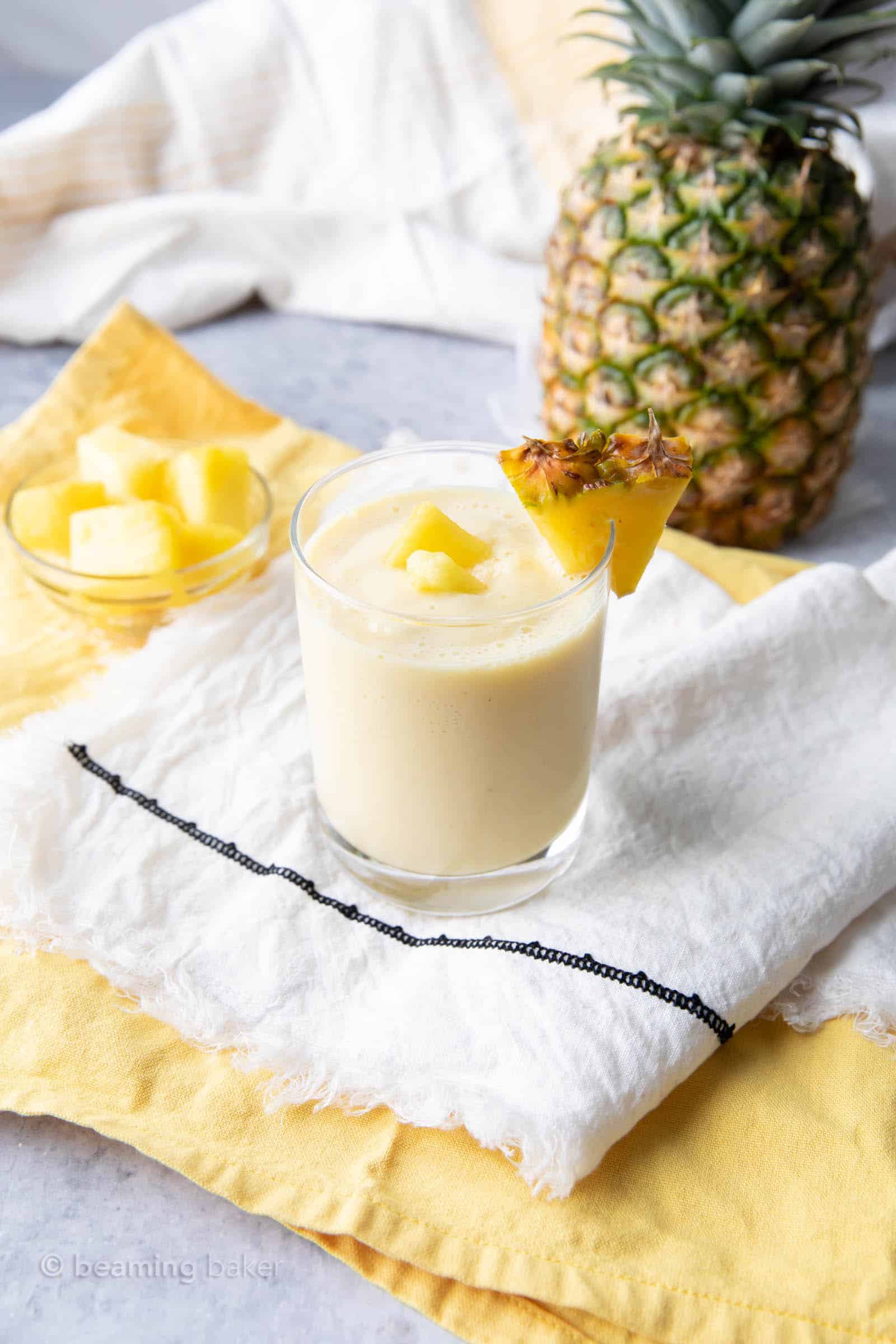 far view of a pineapple smoothie with yogurt on a napkin with a pineapple in the background
