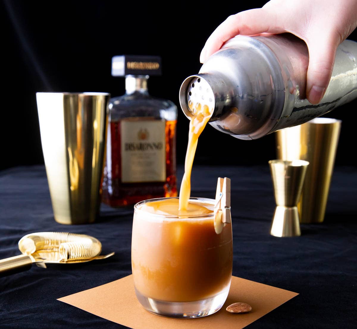 Preparing a Toasted Almond with Disaronno, a gold cocktail shaker, and cocktail tools