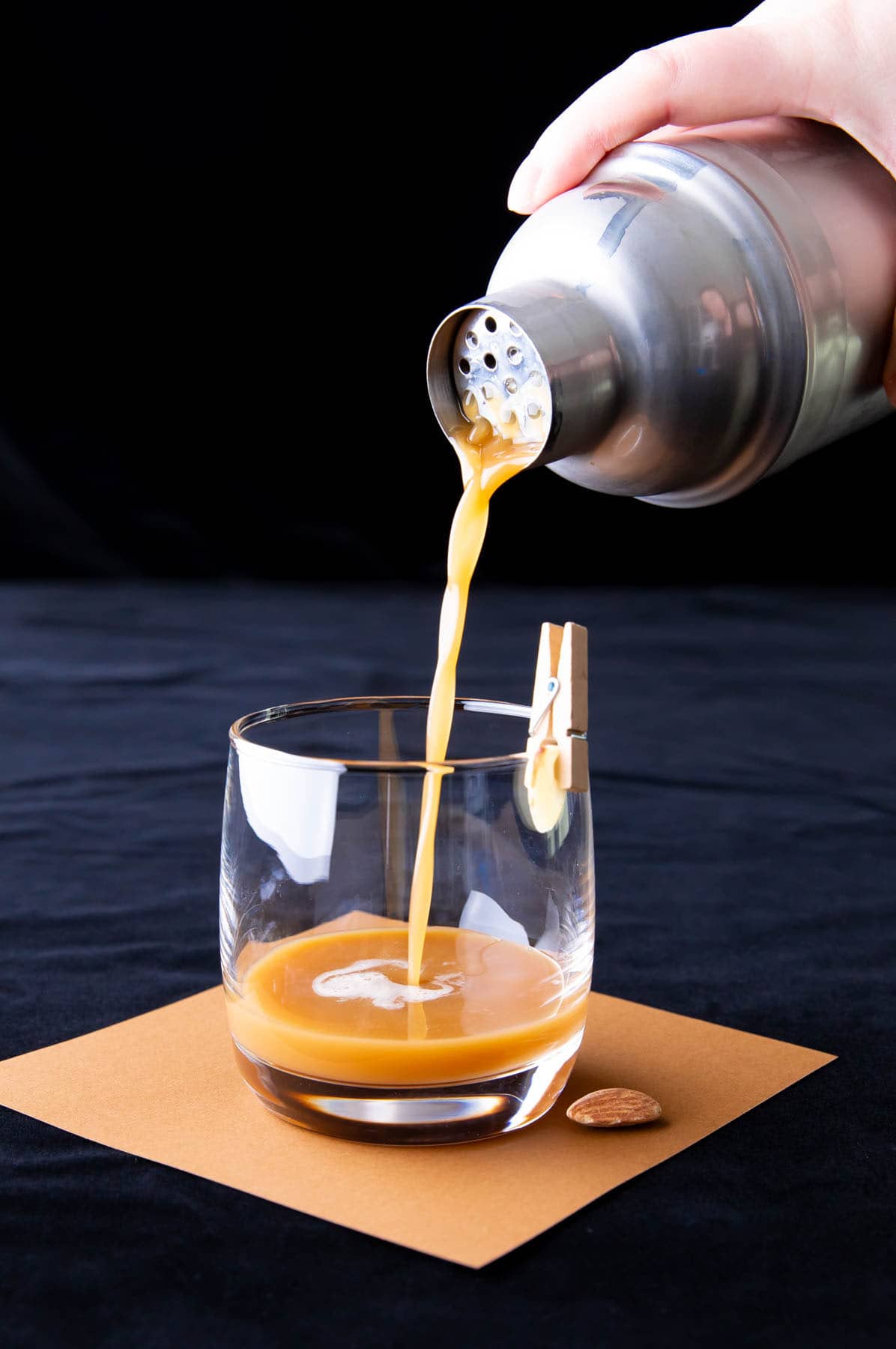 A photo showing how to make a Toasted Almond Drink – straining the cocktail mixture from a cocktail shaker