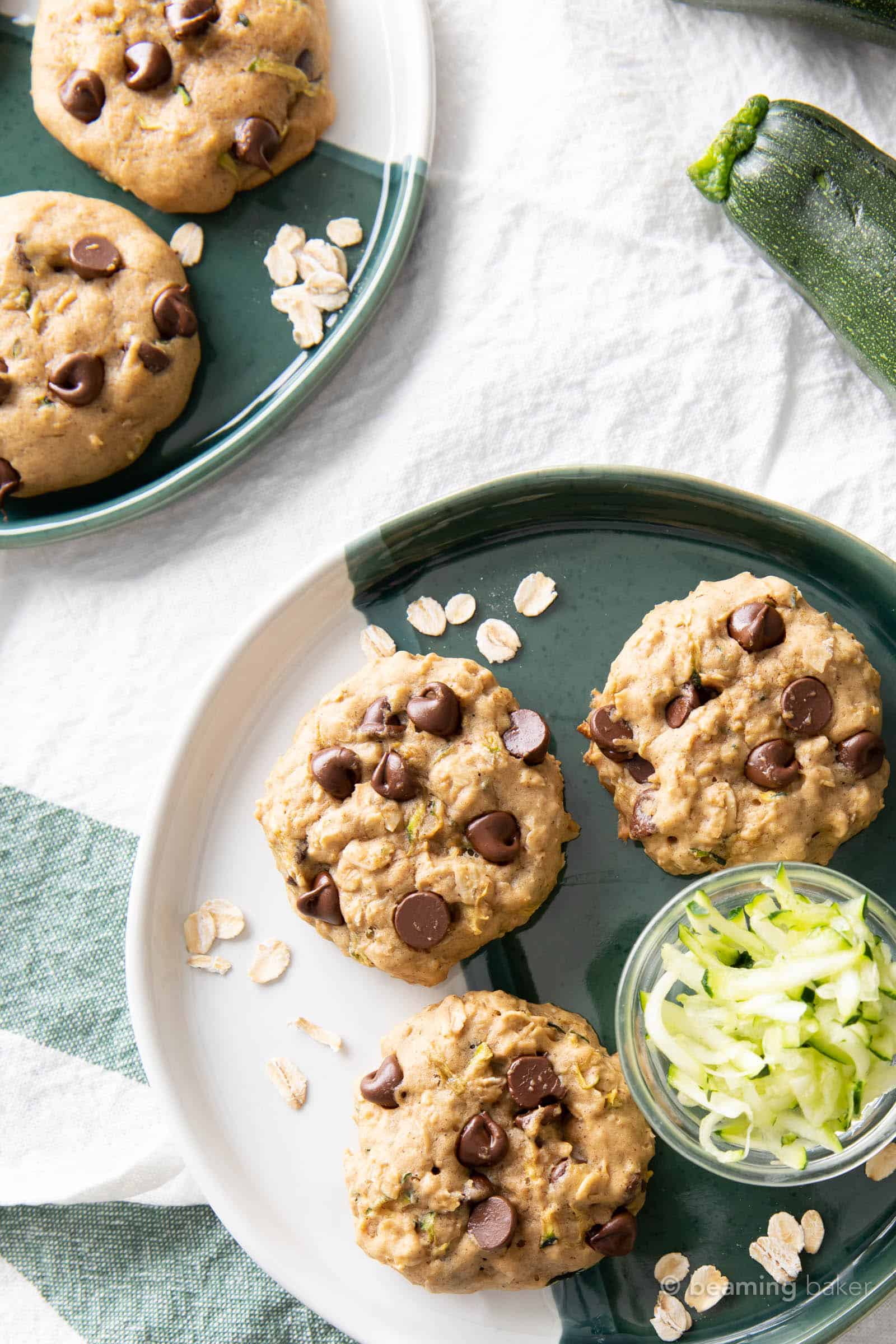 zucchini cookies on a green and white backdrop with a bowl of shredded zucchini